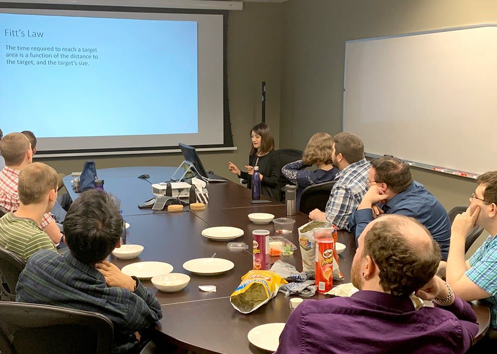 Priscilla presenting a slide on Fitts's law to about a dozen developers around a boardroom table